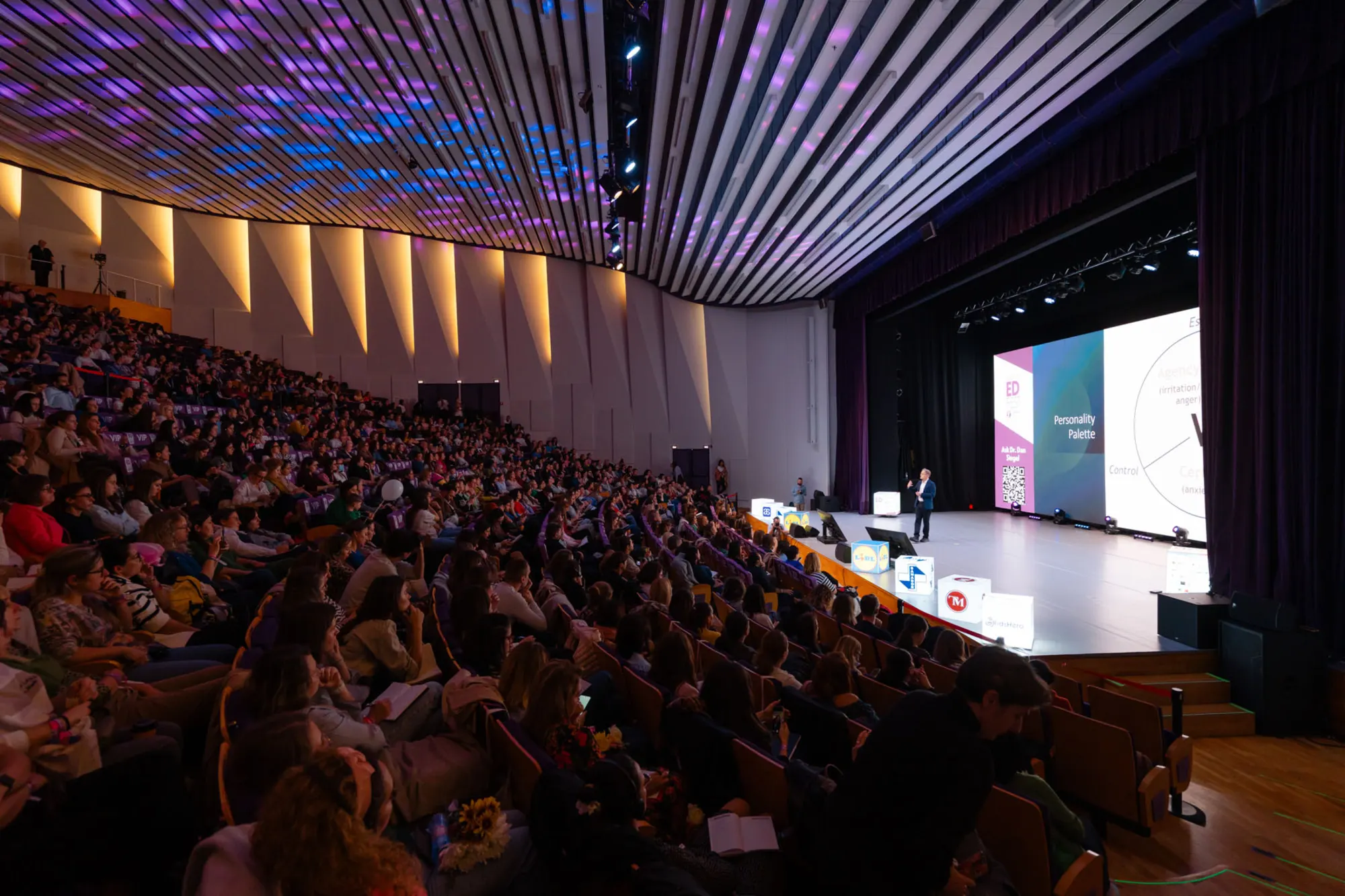 Sala Aula Magna plină de părinți care urmăresc o prezentare pe scena ParentED Fest